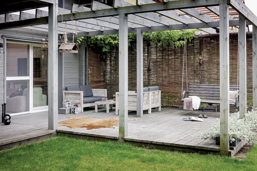 Drewniana weranda wychodzi na kameralny ogród. A w nim zadziwiają różne odmiany ozdobnych traw, są także sosny, dużo sosen,