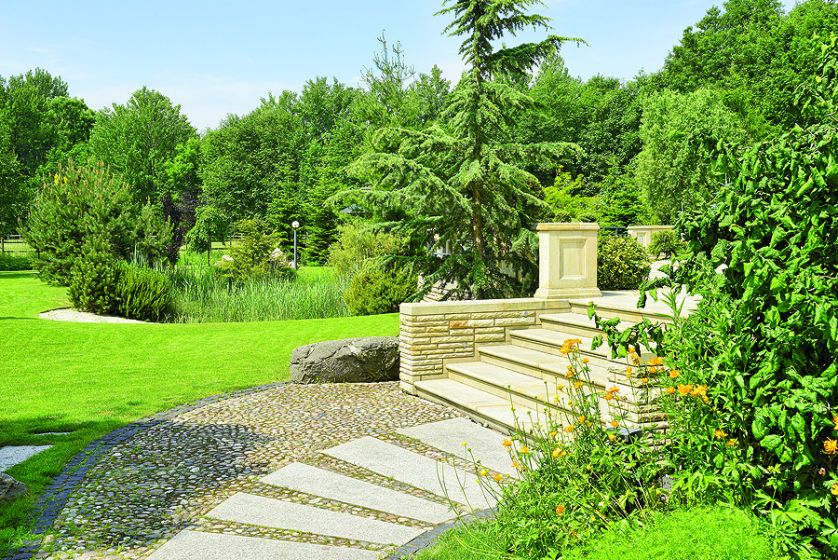 Duży dom w stylu amerykańskich rezydencji znika w bujnej zieleni.
