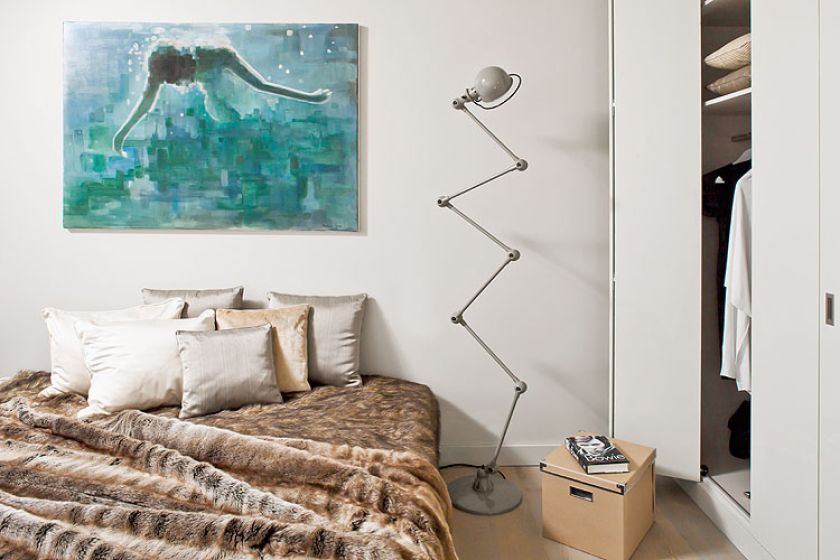 Jedyny kolorowy akcent w beżowo-szarej sypialni to obraz Mariusza Andryszczyka. Obok łóżka stoi kultowa lampa