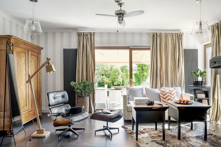 Królem w salonie jest Lounge Chair Eamesów, obok kultowego fotela stoi dizajnerska dębowa lampa z