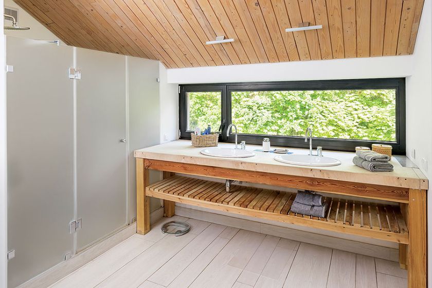 Łazienka w drewnie. Umywalki umiejscowiono pod długim oknem.