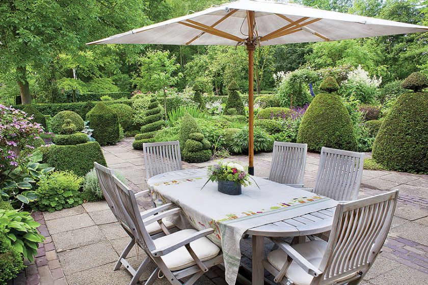 Na tarasie stół, krzesła i parasol - jadalnia pod chmurką.