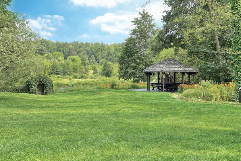 Nad rzekę spływa kaskada liliowców i irysów, która przechodzi w kwietną łąkę.