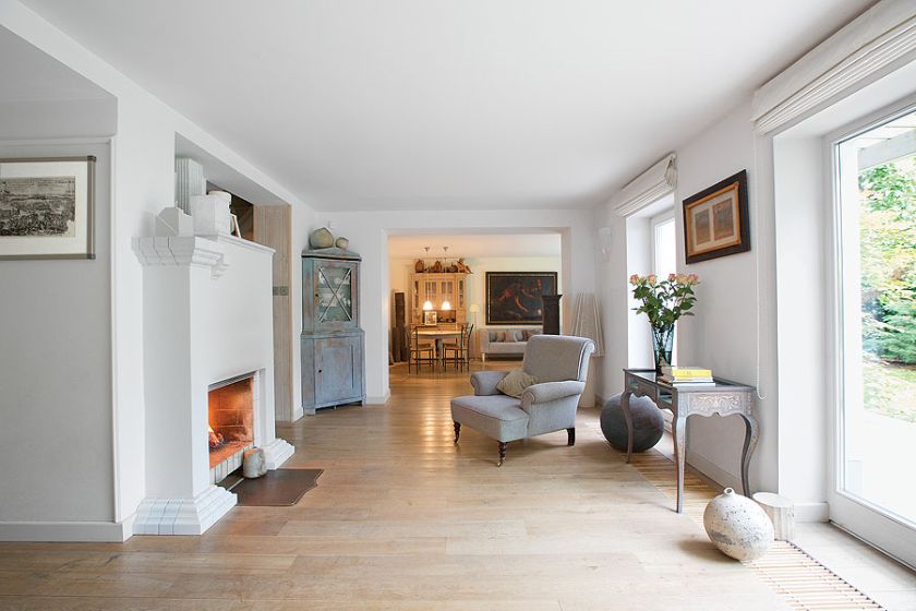 Pośrodku salonu stoi kominek z ceramicznym gzymsem.