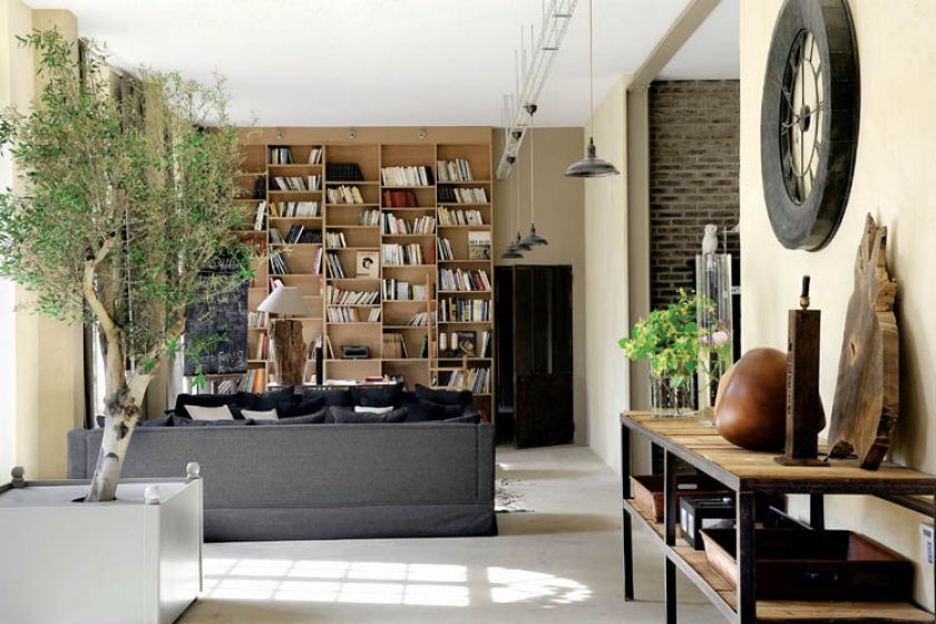 Przytulny salon z biblioteką i teatralnymi dekoracjami.