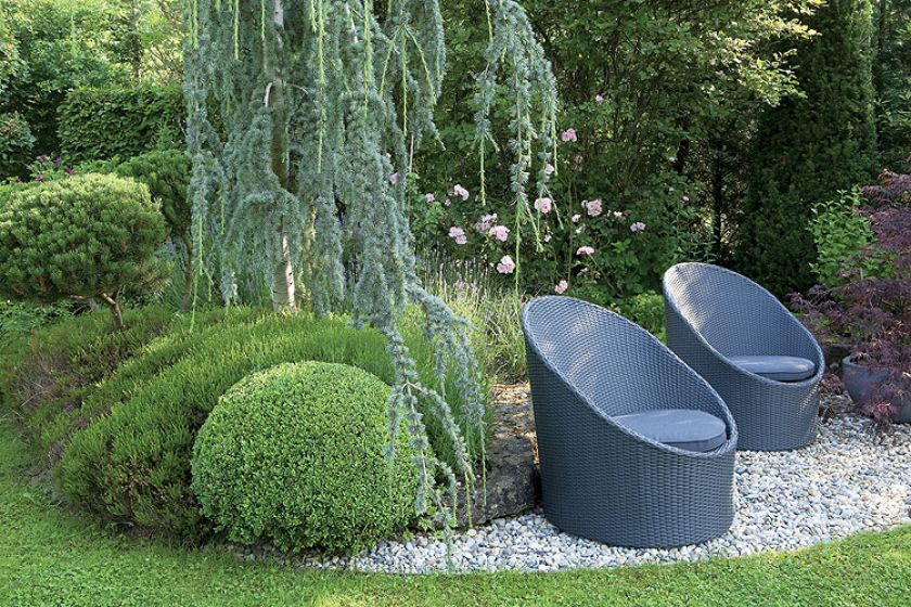 Tradycyjne rośliny, jak bukszpany i róże, połączone są z nowoczesną architekturą. Stąd stalowe elementy i chromowane donice.