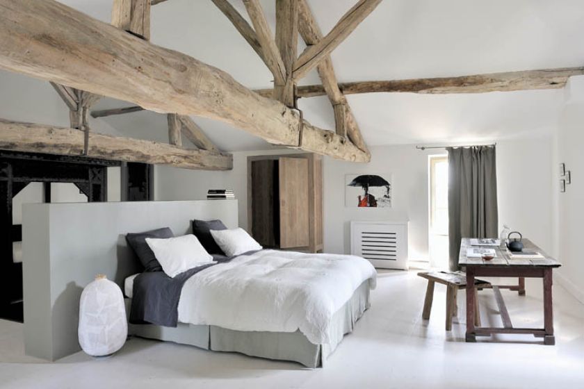 W sypialni króluje wiekowe drewno - od zjawiskowych belek pod sufitem po stolik z zydelkiem. Nawet szafkę na wysokich