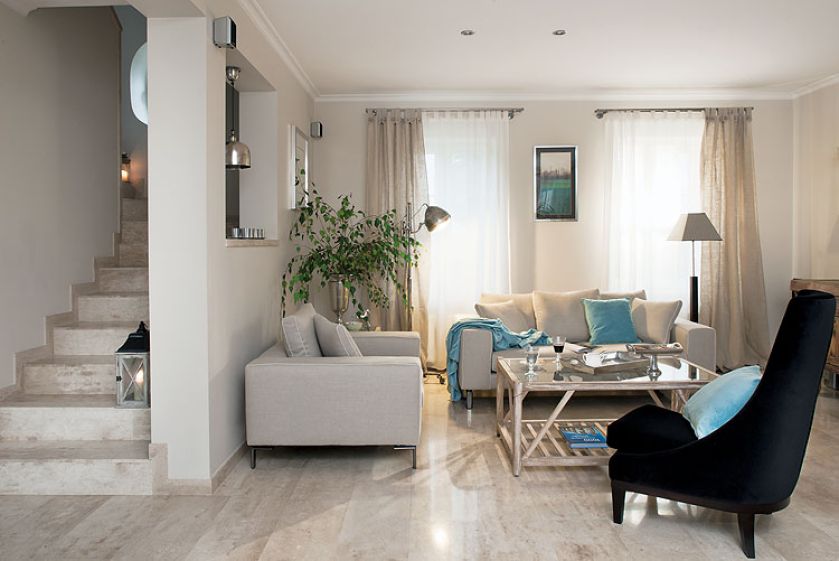 Kremowe sofy, fotele i kawowy stolik z turkusowymi dodatkami.