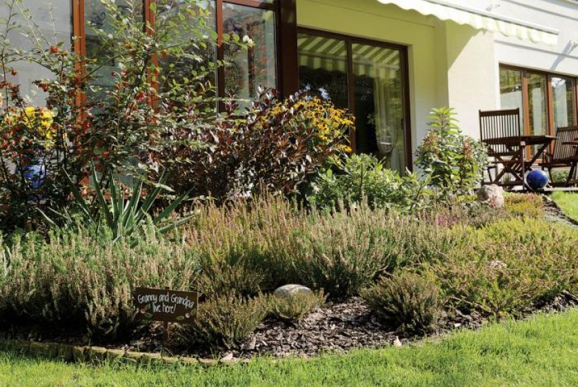 Tabliczka między roślinami. Ogród nad Wilanówką