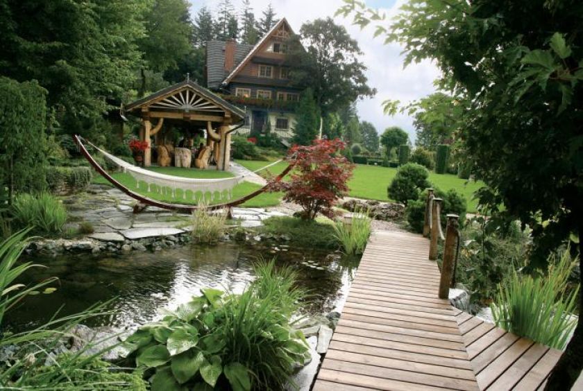 Górny taras ogrodu to szeroki trawnik z altaną i staw z kaskadą, wyglądającą jak górski potok.