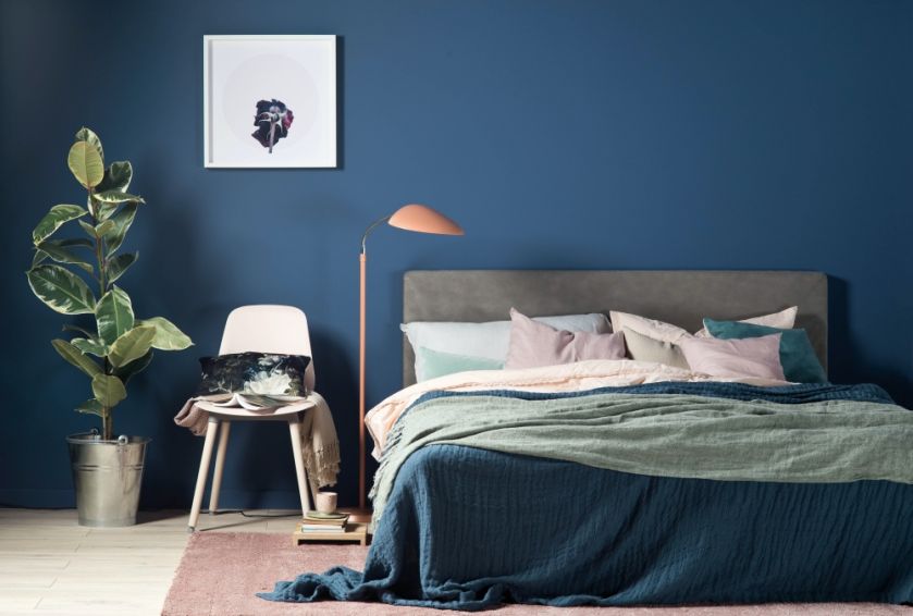 granatowa ściana z obrazami w sypialni