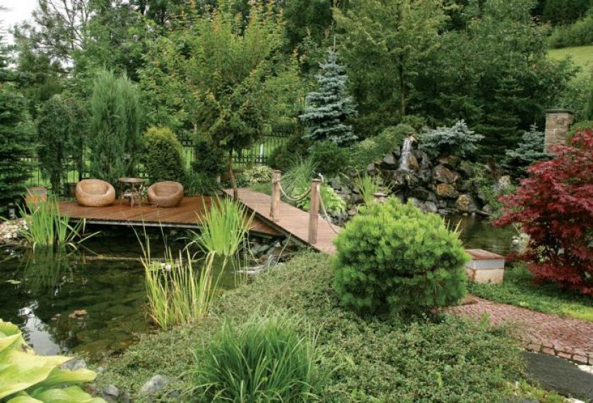 Na pomoście stoją fotele i stolik. Tarasowy ogród otoczony naturą