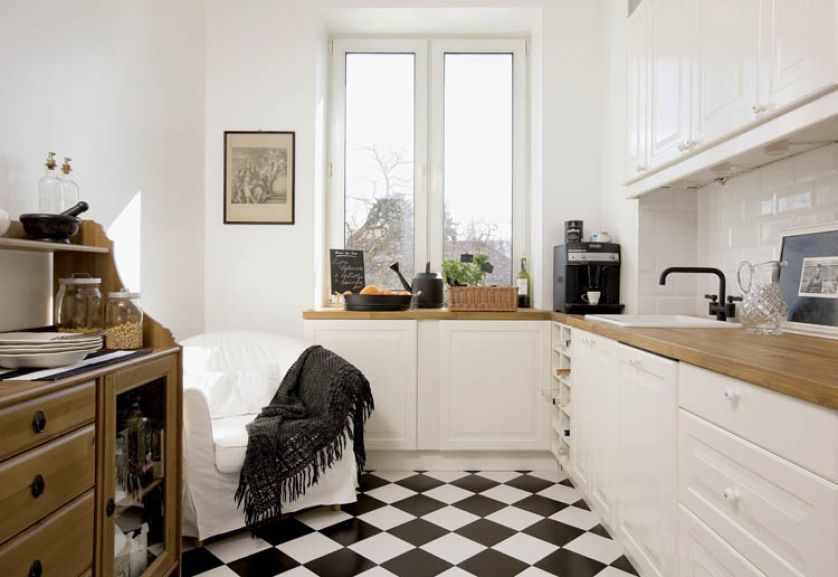 Biel szafek i czerń AGD połączono z ciepłym, dębowym kolorem grubych blatów.