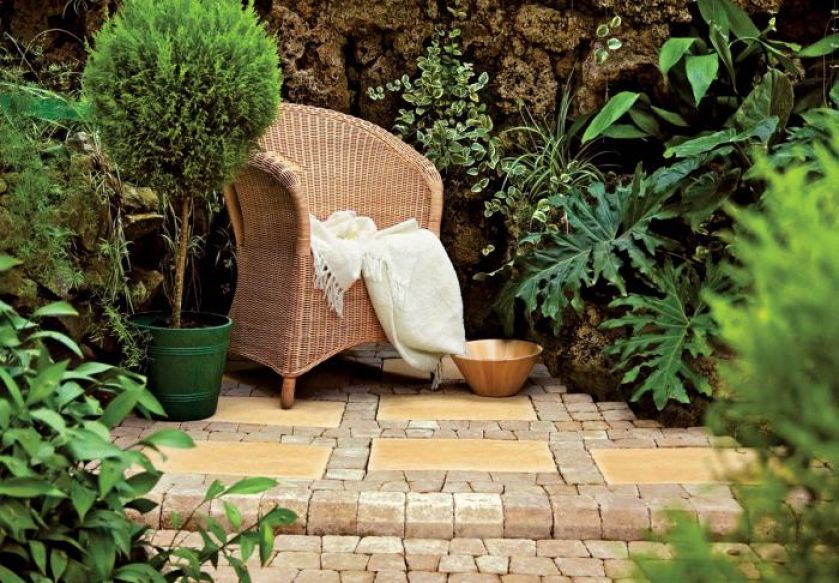 Ratanowy fotel idealnie pasuje do kostki w piaskowym kolorze. Aranżacja LIBET