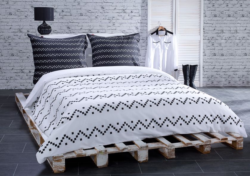 Sypialnia urządzona niskim kosztem: łóżko z palet, na ścianie tapeta imitująca cegły. Minimalizm aranżacji podkreśla