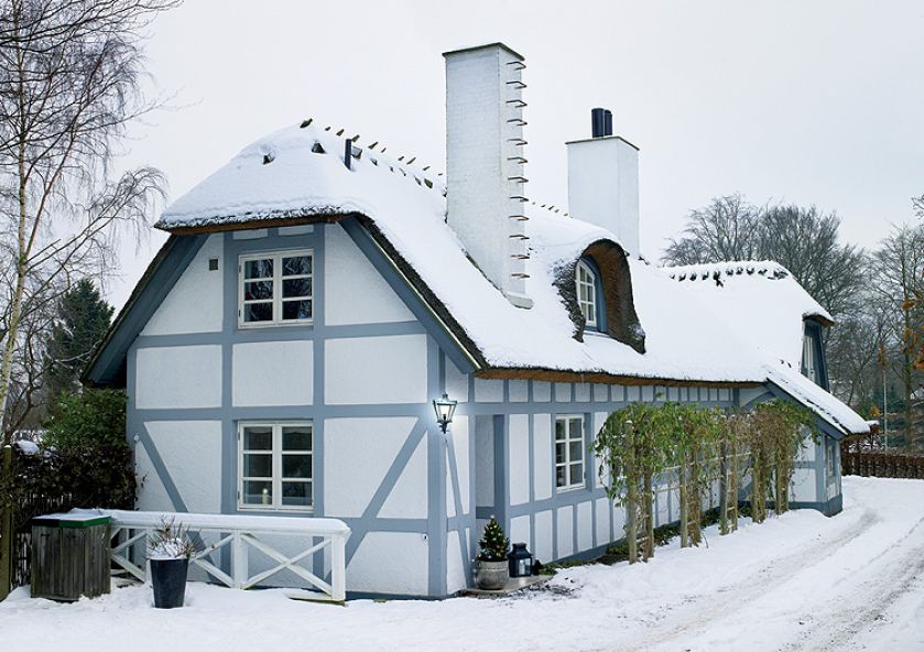 Stuletni dom z dachem krytym strzechą i szarym szkieletem.