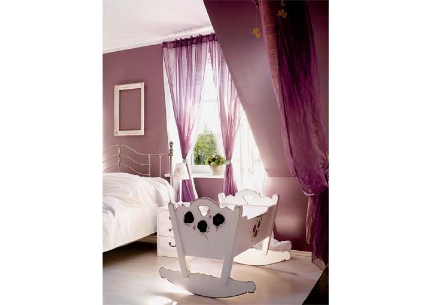 W sypialni stoi rzeźbiona biała kołyska.