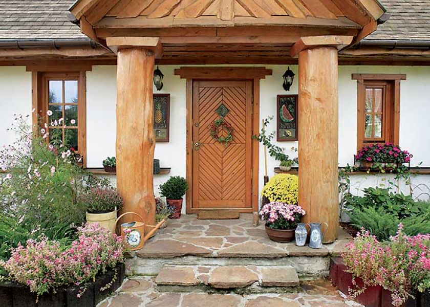 Wejście do domu tonie w kwiatach. W gościnne progi zapraszają sękate kolumny, obrazki, nawet malowane konewki.