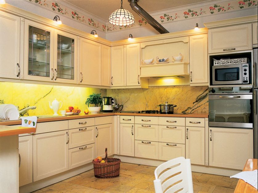 Szafki kuchenne w prowansalskim stylu z uchwytami z ceramicznymi wstawkami. Na ścianie i podłodze żyłkowany kamień.