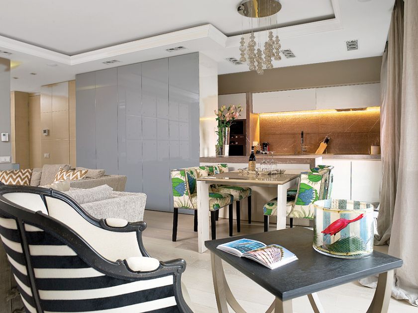 Chłodny kamień i fronty na wysoki połysk ocieplaja krzesła obite lnem marki Christopher Farr.