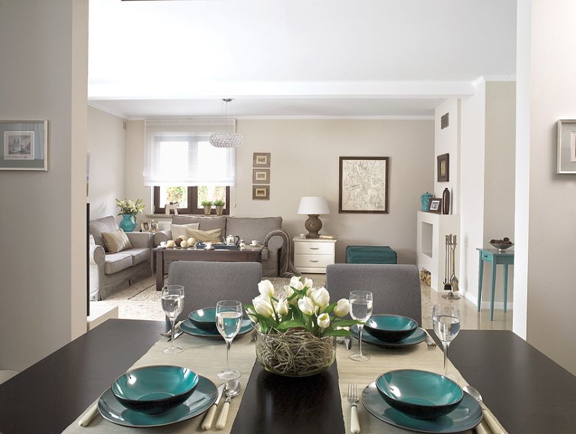 Futrzany koc na pierwszym planie, zastawa stołowa i kwieciste wazony - Almi Decor, dywan w salonie - Belbazaar.