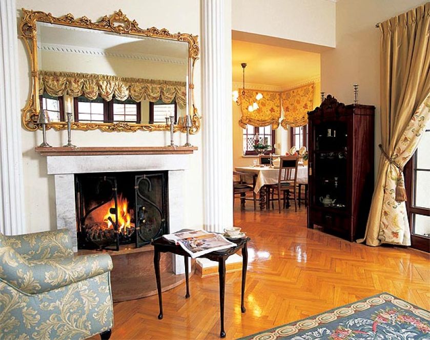 Nad kominkiem wisi lustro w zdobionej ramie.