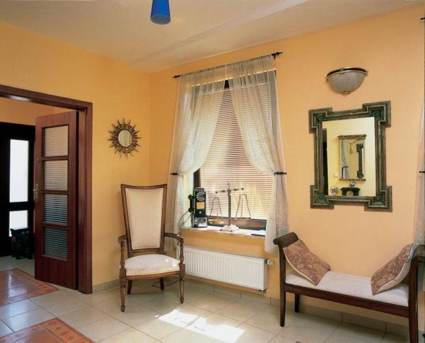 W holu stoi fotel i bankietka. Miejsce dla drobiazgów