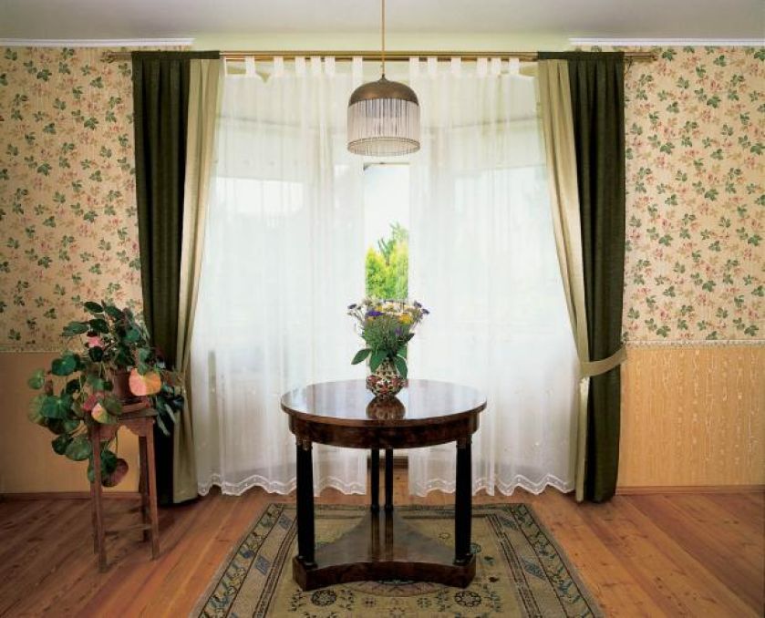 Nad okrągłym stolikiem wisi lampa. Sypialnia po angielsku