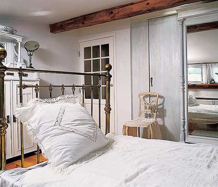 W jasnej sypialni nie mogło zabraknąć łóżka ze zdobionym wezgłowiem.