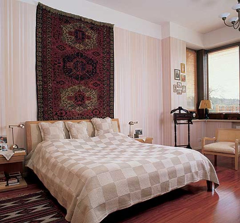 Nad łóżkiem wisi ozdobny dywan. Willa art déco