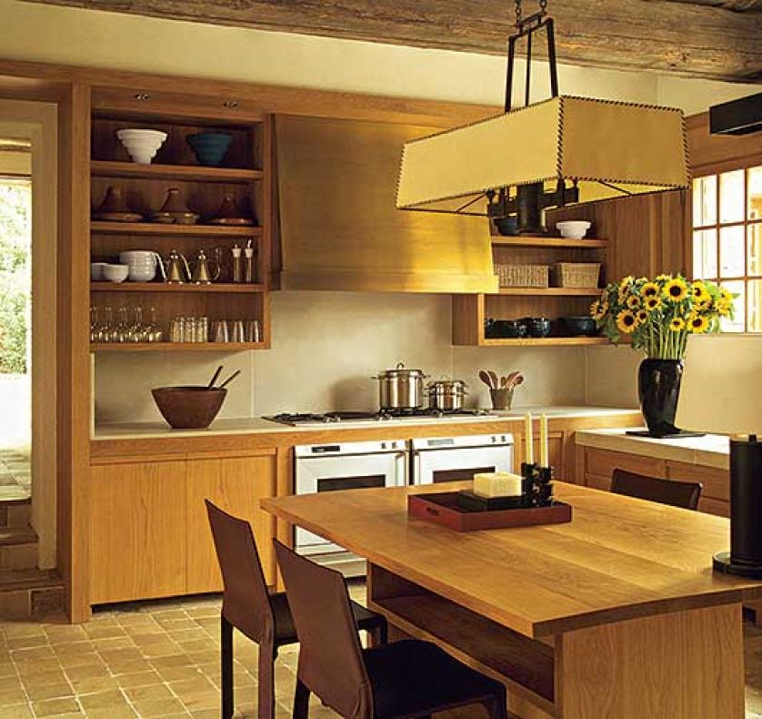 Nad stołem wisi duża lampa. Kamień i drewno w jednym domu