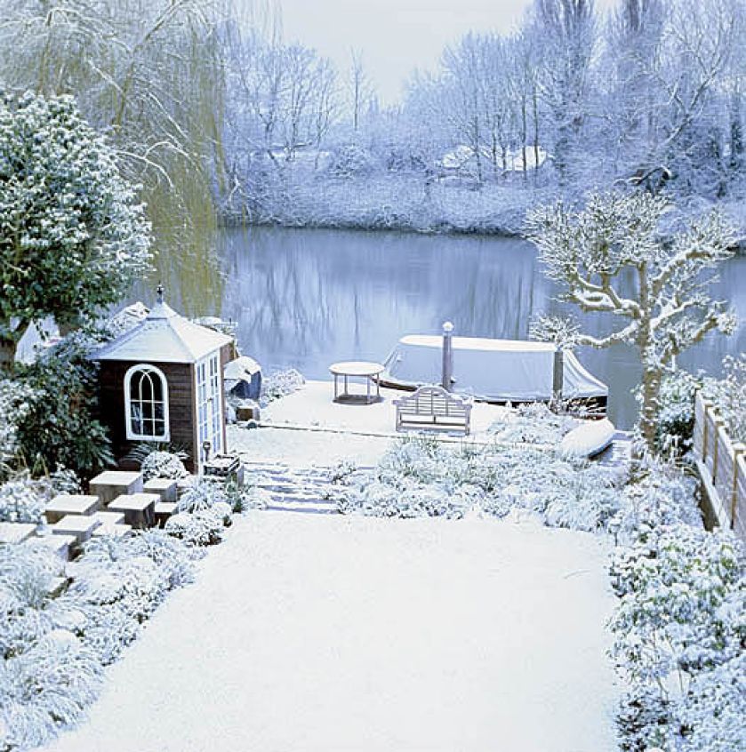 Rzeka, zmrożona, odbija światła domów, które przycupnęły na brzegu.