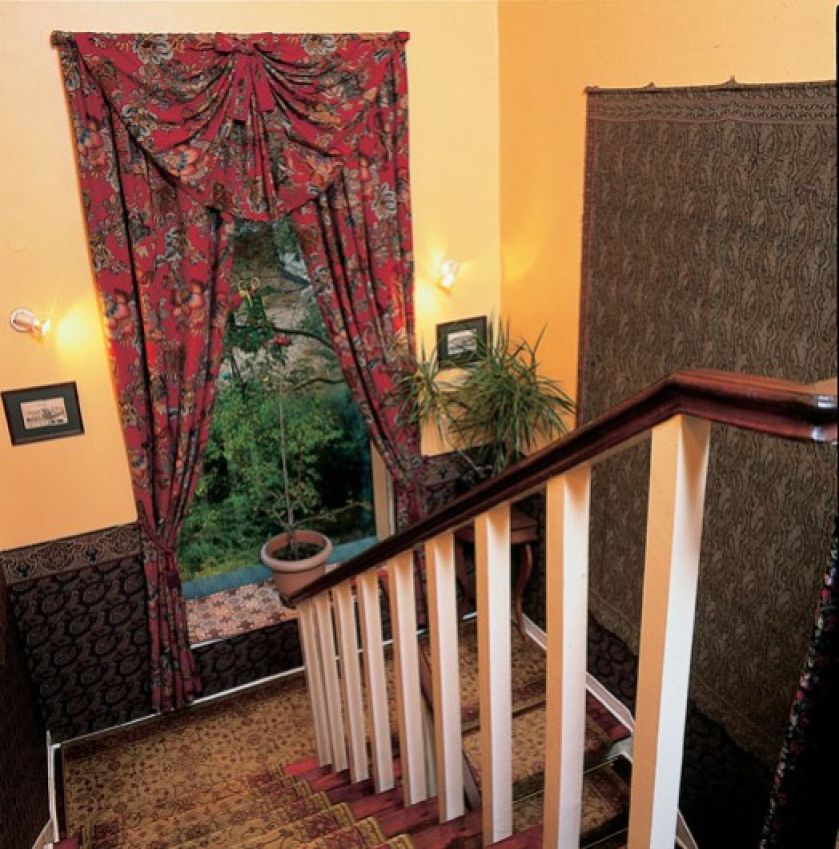 wzorzysty dywan, zasłony i kilim na ścianie - tkaniny sprawiają, że klatka schodowa też jest umeblowana .