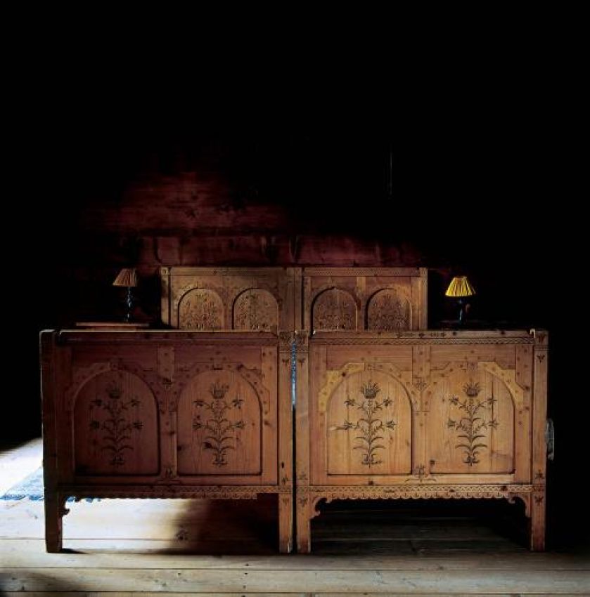 Drewniane łóżko zdobią motywy roślinne.