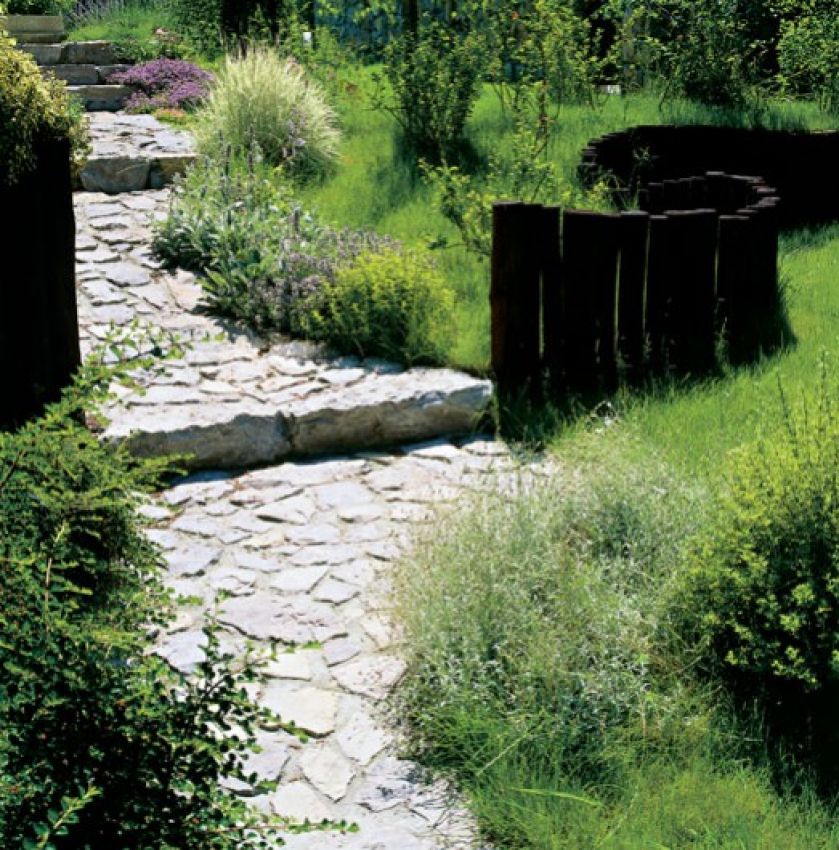 Kręta wapienna ścieżka i rozsiane po trawie wokół kępki ozdobnych roślin sprawiają, że przechodząc tędy