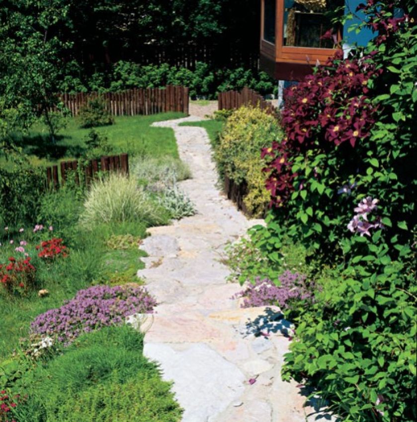 Nierówna, wyłożona kamieniem alejka, drewniane płotki i kępki roślin rozsiane, jakby same tak wyrosły - ot, wiejski ogródek.