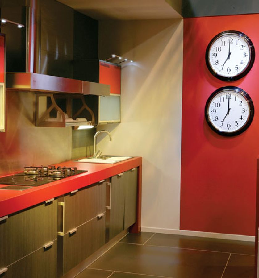 Zegar w kuchni jest niezbędny, ale dwa to już ekstrawagancja. Podobnie jak czerwona ściana i dobrany pod kolor blat