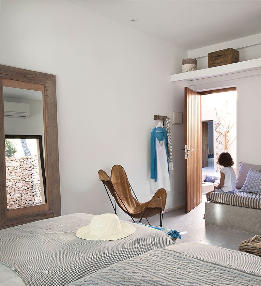 Skórzany dizajnerski fotel i wielkie lustro oparte o ścianę.